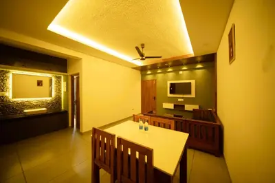 a dining room with a white table and chairs at Spezio Luxurious Apartments in Perintalmanna