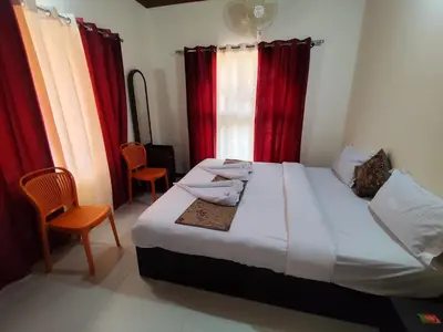 a bedroom with a large bed with red curtains at RajPari Stay in Madikeri