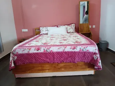 a bedroom with a bed with a pink wall at Willow Nest Cottages in Vattavada
