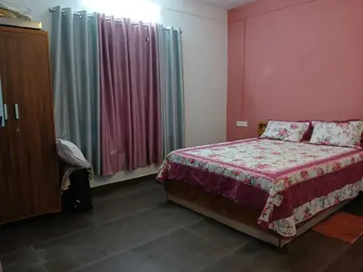 a bedroom with a bed and a window with curtains at Willow Nest Cottages in Vattavada