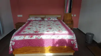 a bedroom with a bed with a pink and white bedspread at Willow Nest Cottages in Vattavada