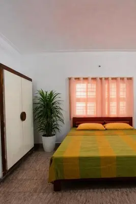 a bedroom with a bed and a potted plant at Nele Mane in Mysore