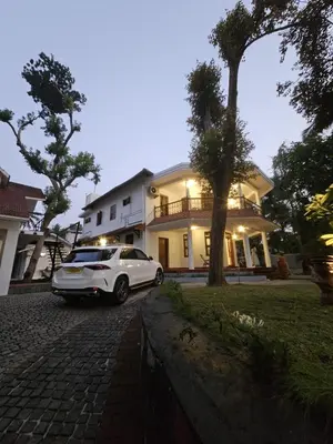 a white car parked in front of a house at Souparnika Heritage in Tellicherry
