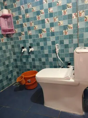 a bathroom with a toilet and a blue tiled wall at Dreams home estate stay coorg in Suntikoppa