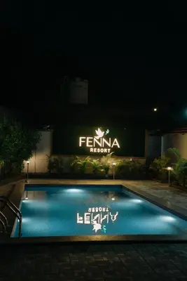 a swimming pool in front of a building at night at Fenna Resort And Spa, coorg in Kushālnagar