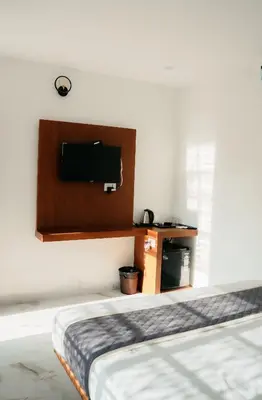 a bedroom with a bed and a tv on the wall at Fenna Resort And Spa, coorg in Kushālnagar