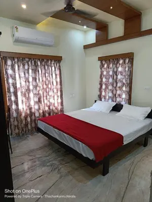 a bedroom with a large bed with red sheets and curtains at Kalariyullathil Homestay