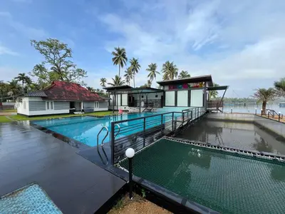 a swimming pool with a house and a building at Aquatica Farms in Kodungallūr