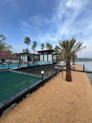 a resort with a swimming pool and a palm tree at Aquatica Farms in Kodungallūr
