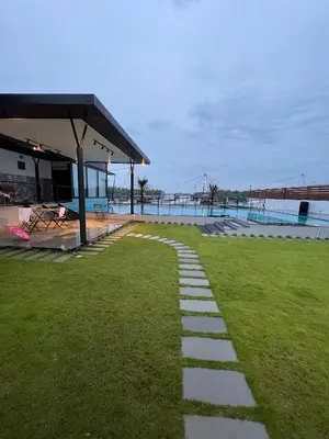 a walkway in the grass next to a building at Aquatica Farms in Kodungallūr