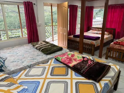 a living room with two beds and a room with windows at Joys Santa in Vattavada