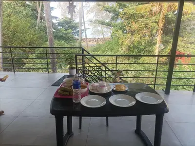 a table with plates of food on a balcony at Kghomestay in Pallipuram