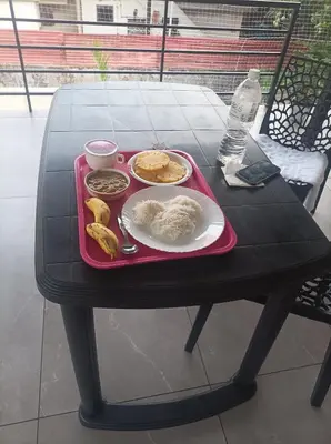 a table with a red tray with food on it at Kghomestay in Pallipuram
