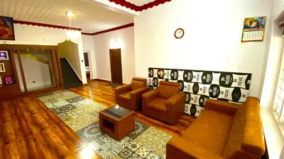 a living room with a couch and chairs in it at Karmalhills Homestay in Tindummal