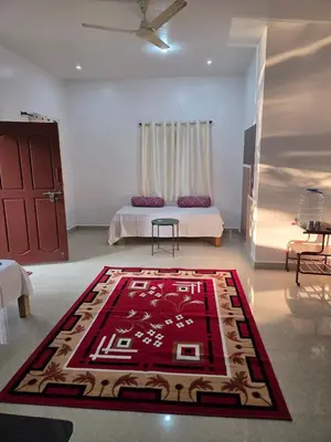 a bedroom with a bed and a rug on the floor at Pearl Farmstay in Kushālnagar