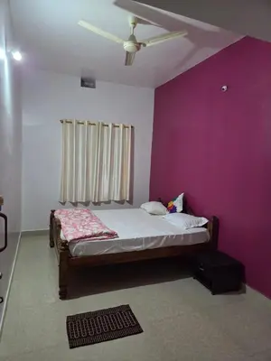 a bedroom with a bed and a ceiling fan at Pearl Farmstay in Kushālnagar