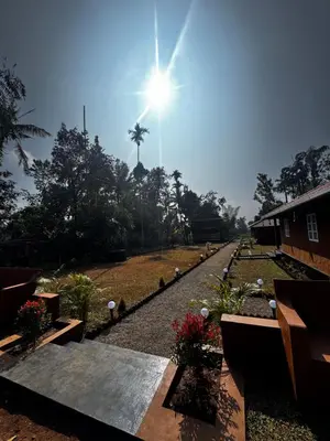 a sun shining over a garden with a palm tree in the background at Marayoor Mud Castle in Marayoor