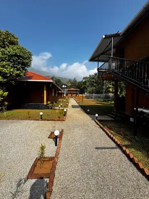 a walkway in front of a building with a house at Marayoor Mud Castle in Marayoor