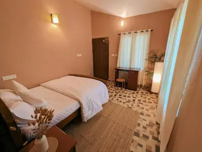 a small bedroom with a bed and a table at Uravu by LAKOTA in Chekadi