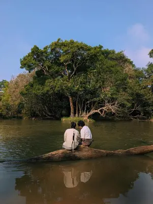 two men sitting on a boat in the water at Uravu by LAKOTA in Chekadi