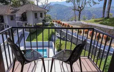 a balcony with two chairs and a table and a view at Rippon Mount Resorts in Meppādi