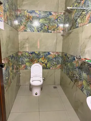 a bathroom with a white toilet in a stall at ACK River Palms - Athirappilly in Athirappally