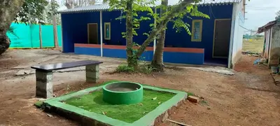 a building with a green bucket in a dirt yard at Home stay in Mysore