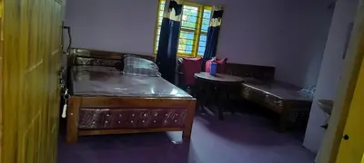 a room with a bed and a table and a window at Home stay in Mysore