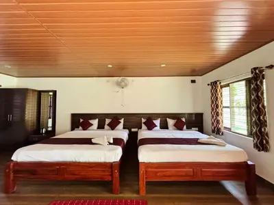 a bedroom with two beds and a wooden ceiling at Phalam Homestay in Kushālnagar
