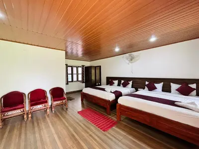 a bedroom with two beds and two red chairs at Phalam Homestay in Kushālnagar