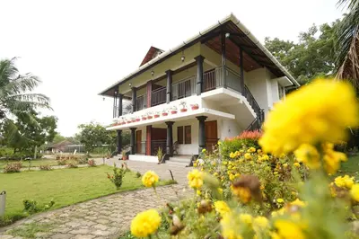 a house with flowers in front of it at Mango Village Resort in Kollengode