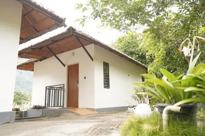 a small white house with a wooden door at Mango Village Resort in Kollengode
