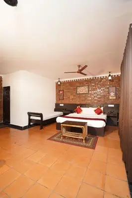 a bedroom with a bed and a brick wall at Mango Village Resort in Kollengode