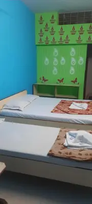 two beds in a room with a green wall at Friends Residency Mysuru in Mysore