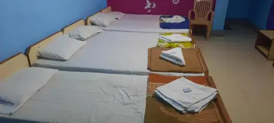 three beds in a room with towels on them at Friends Residency Mysuru in Mysore