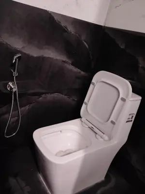 a white toilet in a bathroom with a black wall at Golden Valley Abode in Siddapur