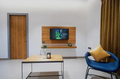 a living room with a table and a tv on a wall at Nes-Terns in Coimbatore