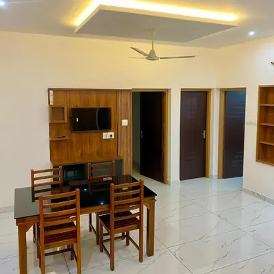 a dining room with a table and chairs and a tv at KM Villa in Kottakkal