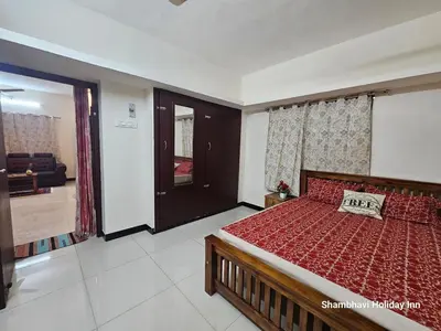 a bedroom with a bed with a red comforter at SHI's Krishna 2BHK Villa Furnished Cozy Stay in Coimbatore