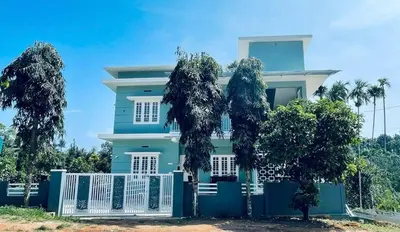 a blue house with trees in front of it at The Karlyle Homestay in Sultan Bathery