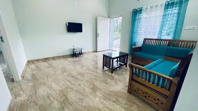 a living room with a blue couch and a tv at The Karlyle Homestay in Sultan Bathery