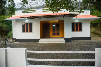 a small white house with a orange door at The Elephant watch in Viripara