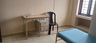 a room with a desk and a chair and a bed at Sithara Guest House in Palakkad