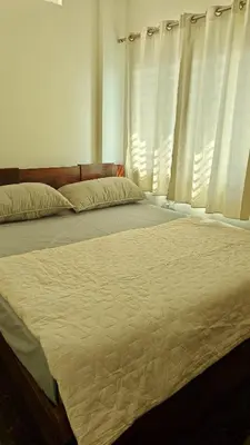 a bed in a bedroom with white curtains at Gamani in Mysore