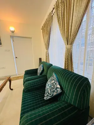 a green couch with pillows in a living room at Little Home By D2V in Ooty