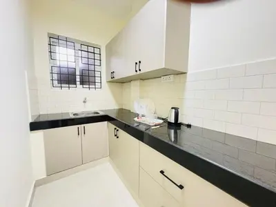 a kitchen with white cabinets and a black counter top at Little Home By D2V in Ooty