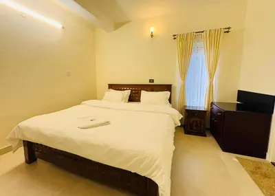 a bedroom with a large bed and a television at Little Home By D2V in Ooty