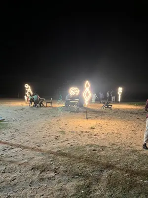 a group of people sitting on benches at night at Ichakkans beach resort in Irimbranallūr
