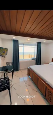 a bedroom with a bed and a desk and a window at Ichakkans beach resort in Irimbranallūr