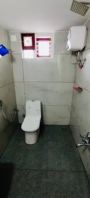 a small bathroom with a toilet in a stall at AGNEYA Holiday Home in Wayanad